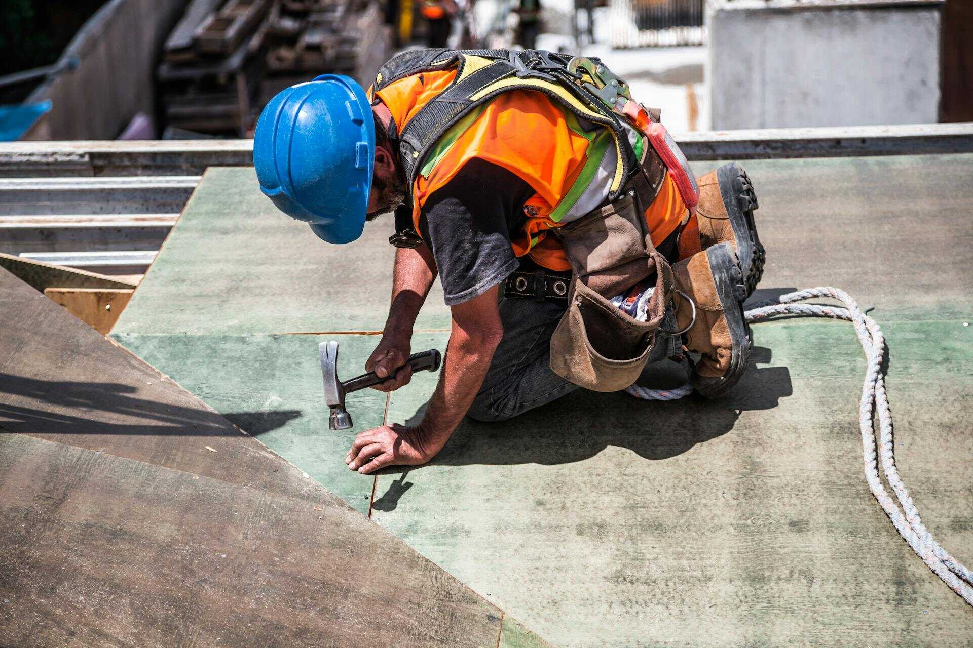 A roofing contractor in Atlanta wearing a blue hard hat using a hammer