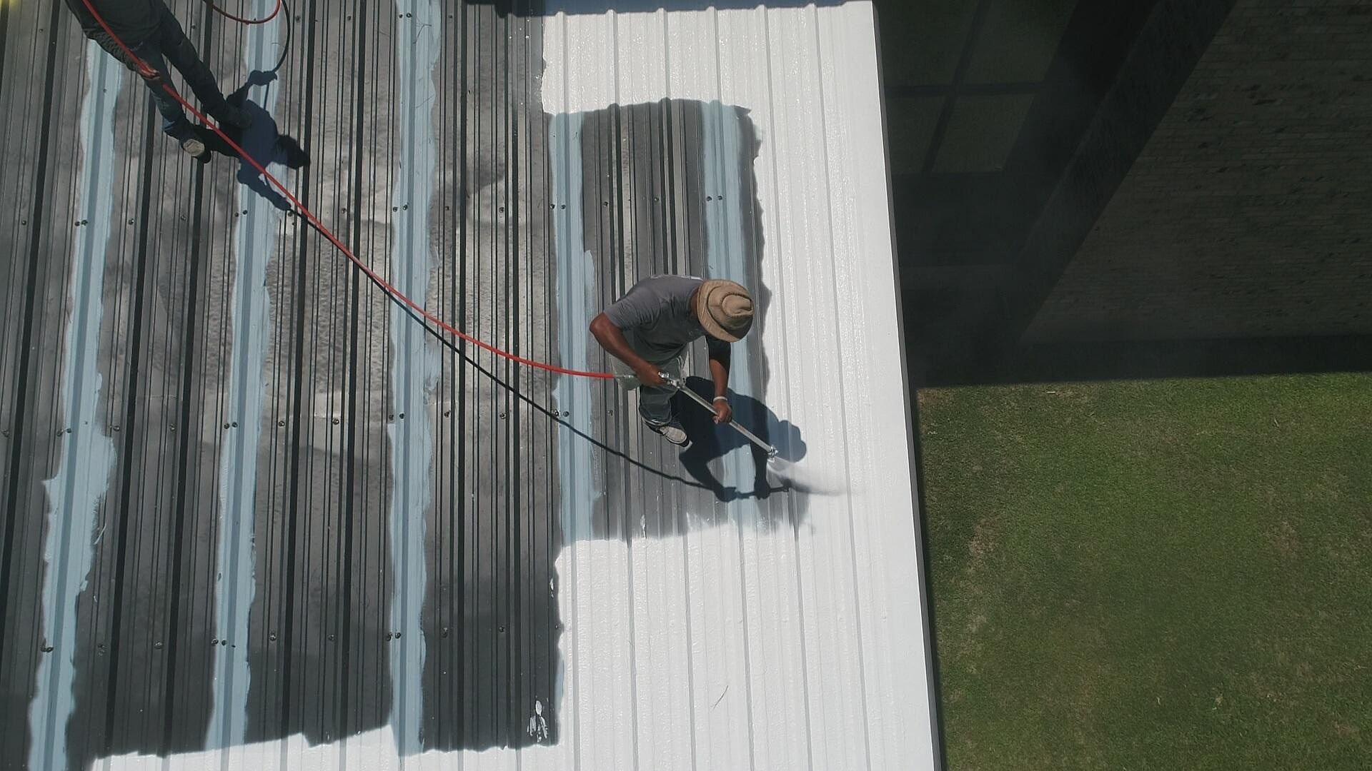 A team of TPO installers spreading a silicone coating on a commercial roof in Atlanta